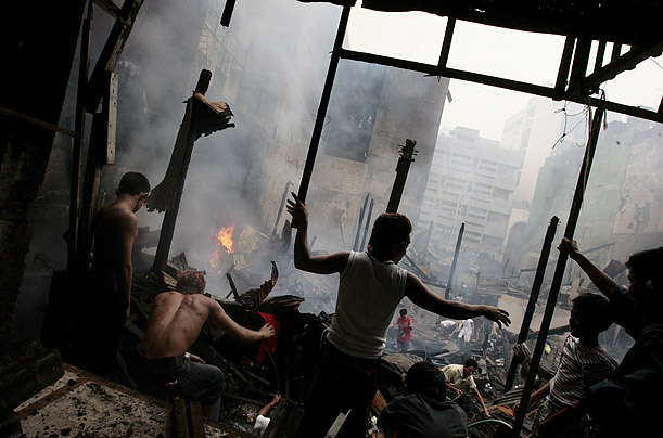 People inspect the site of a fire that razed houses at Manila's Binondo district in the Philippines