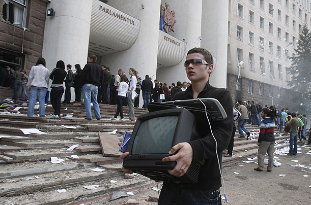 looter carries a television out of the parliament building in Chisinau, Moldova during a protest denouncing a Communist election victory