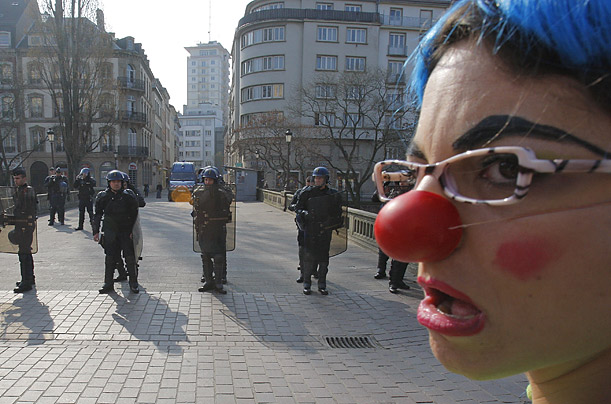 An anti-NATO activist dressed as a clown faces riot police blocking the access to a bridge in downtown Strasbourg, France, during NATO's 60th-anniversary summit.