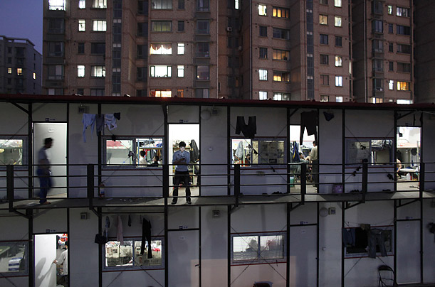 A migrant construction worker checks his mobile phone outside his dormitory after working a shift at the Shanghai World Expo 2010 construction site.
