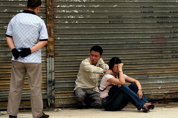 A Chinese policeman tries to convince a knife-wielding man to release a hostage on a street in Guangzhou, China. The man and his brother kidnapped the passer-by in a desperate bid to raise money for their mother's medical treatment.