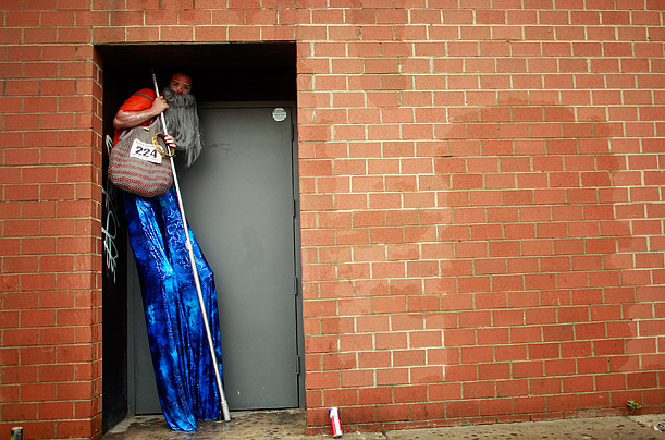 A man on stilts hides from the rain before the start of the 2009 Mermaid Parade at Coney Island, which pays homage