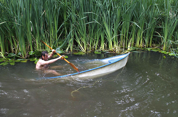 A man struggles to paddle his sinking boat in a lake in Szandavaralja, Hungary.