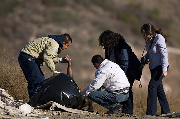 Remains
Forensic examiners place the body of an unidentified man into a plastic bag on the outskirts of Tijuana, Mexico. The police